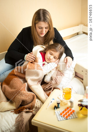 caring mother hugging sick girl lying in bed caring mother hugging sick girl lying in bed 16746655