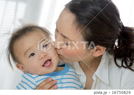 リビングで母親にキスされる赤ちゃんの写真素材