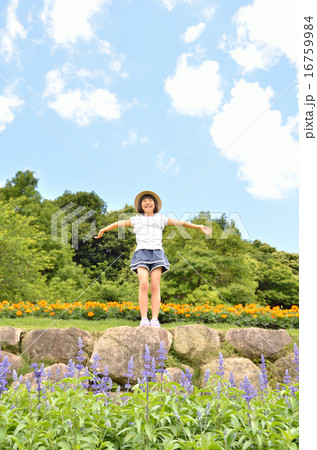 花畑で手を広げる女の子 麦わら帽子 の写真素材