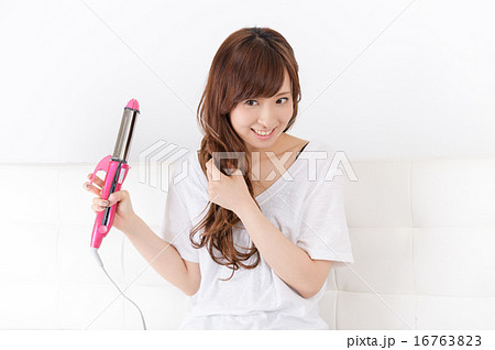 ヘアアイロンを使う若い女性 16763823