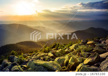 Misty mountains with green stones in the foreground 16765100