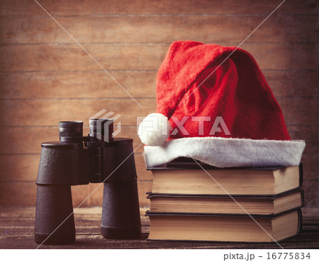 Santas hat over books near black binocular Santas hat over books near black binocular 16775834