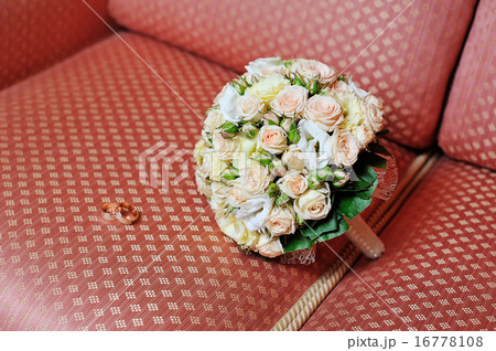 Pair of wedding rings and wedding bouquet on sofa Pair of wedding rings and wedding bouquet on sofa 16778108