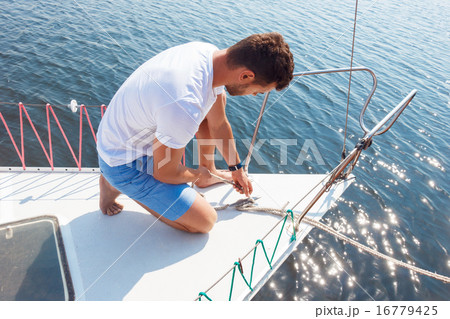 Positive man adjusting his yacht  16779425