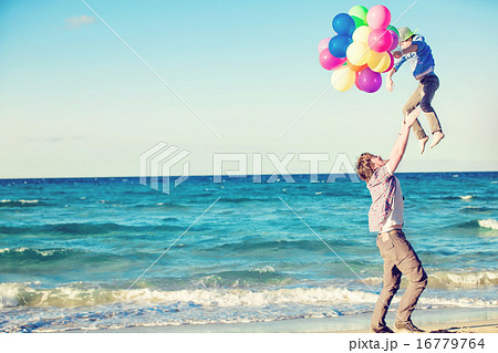 Happy father and son having great time on the beach in sunset light 16779764