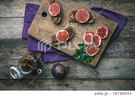 Cut figs and bread with jam on choppingboard 16788043