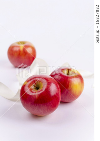 Three red apples on white background and ribbon 16827882