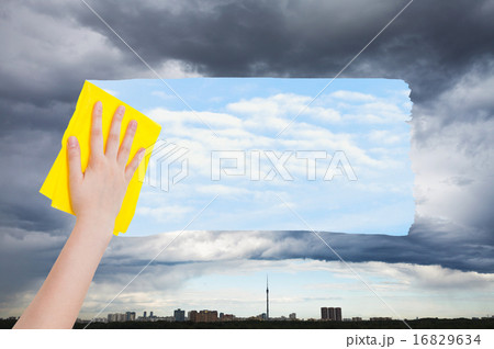 hand deletes rainy cloud over city by yellow cloth 16829634
