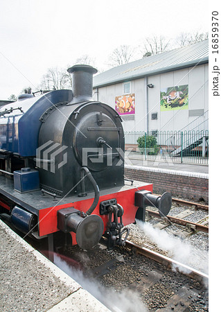 イギリス田舎の観光地の蒸気機関車 煙を吐いて駅に到着の写真素材