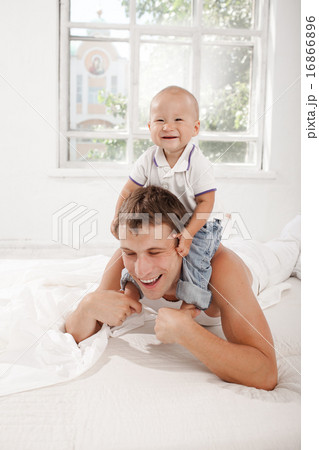 young father with his nine months old son on the bed at home 16866896