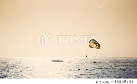 Parasailing on parachute over water at sunset 16869243
