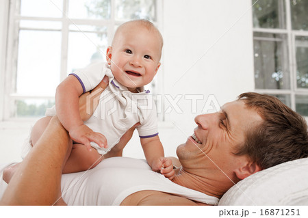 young father with his nine months old son on the bed at home young father with his nine months old son on the bed at home 16871251