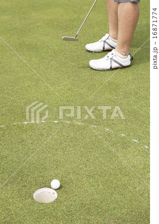 Golf player putting ball into hole Golf player putting ball into hole 16871774