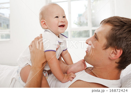 young father with his nine months old son on the bed at home 16872424