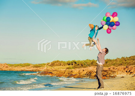 Happy father and son having great time on the beach in sunset light 16876975
