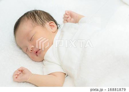白い産着にくるまれて眠っている新生児 16881879