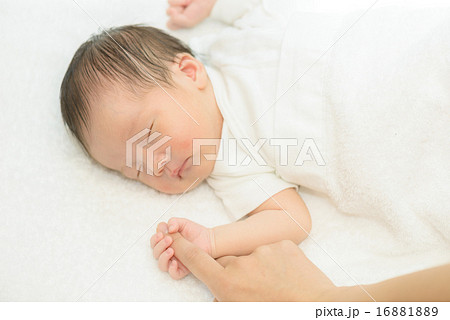 白い産着にくるまれて眠っている新生児 16881889