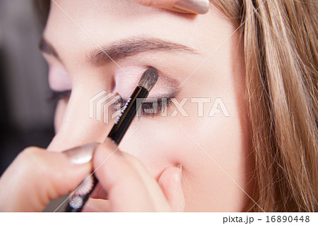 Stylist doing professional makeup of young woman. Close up 16890448