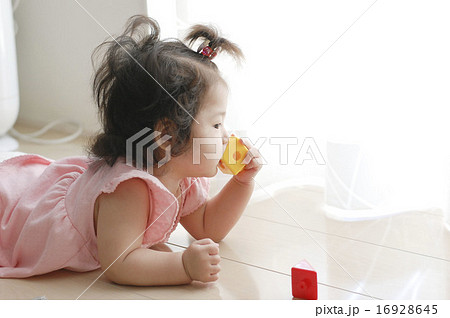 おもちゃを口に入れる赤ちゃんの写真素材