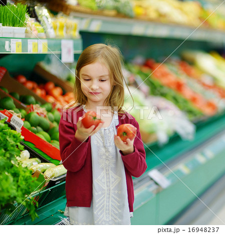 Little girl choosing tomatoes in a food store Little girl choosing tomatoes in a food store 16948237