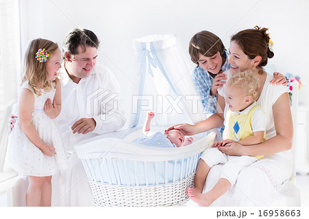 Family playing with newborn child in white bassinet Family playing with newborn child in white bassinet 16958663