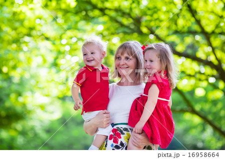 Mother holding two kids walking in summer park 16958664