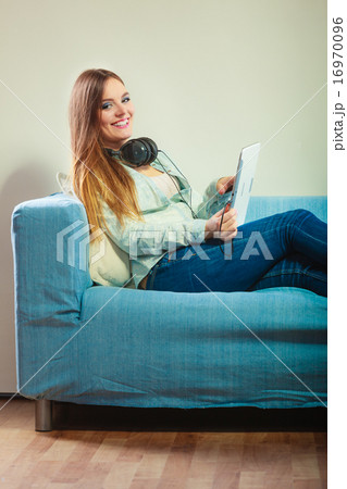 Woman with tablet headphones sitting on couch Woman with tablet headphones sitting on couch 16970096