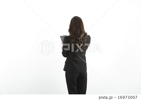 タブレット 若い女性 後姿 ビジネスウーマン パンツスーツ 白バックの写真素材