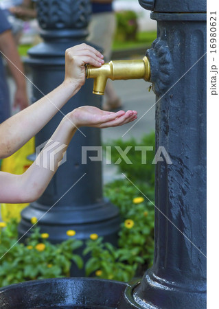 Closeup photo of girl hands push a city fountain Closeup photo of girl hands push a city fountain 16980621
