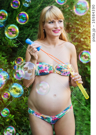 Pregnant girl is making bubbles outdoors Pregnant girl is making bubbles outdoors 16984390