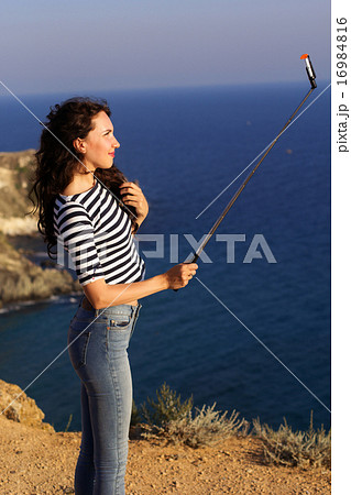 Pretty slim girl making selfie photo with stick on mountain 16984816