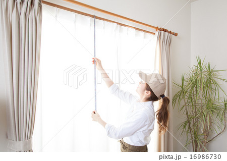 窓のカーテンのサイズを測る女性 16986730