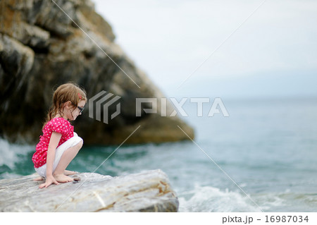 Adorable little girl sitting on a rock Adorable little girl sitting on a rock 16987034