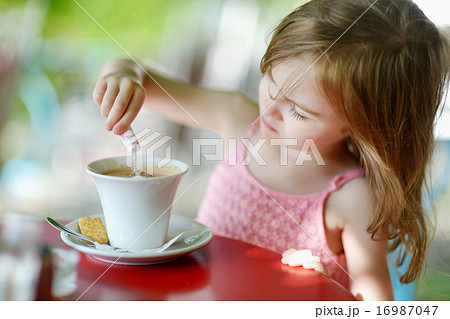 Little girl pouring sugar into hot chocolate 16987047