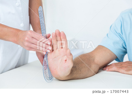 Doctor measuring wrist with goniometer Doctor measuring wrist with goniometer 17007443