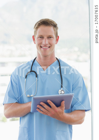 Happy doctor writing on clipboard beside windows 17007635