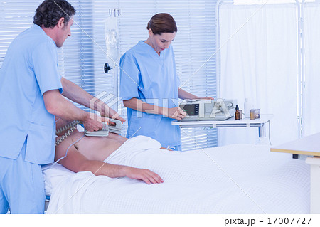 Medical team resuscitating a man with a defibrillator 17007727