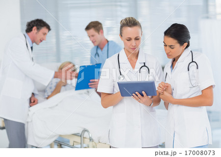 Doctors looking at clipboard while theirs colleagues speaks with Doctors looking at clipboard while theirs colleagues speaks with 17008073