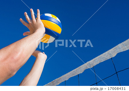 Man throwing volleyball above the net 17008431