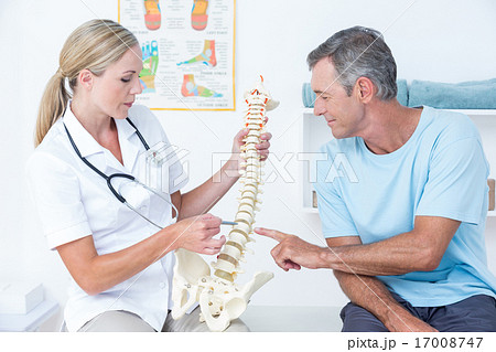 Doctor showing her patient a spine model Doctor showing her patient a spine model 17008747