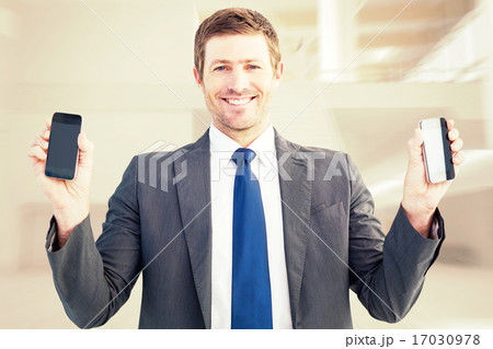 Composite image of businessman holding two smart phones Composite image of businessman holding two smart phones 17030978