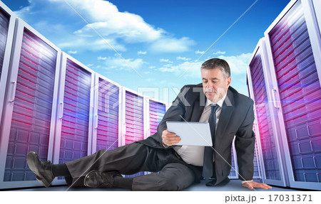 Composite image of mature businessman sitting using tablet 17031371