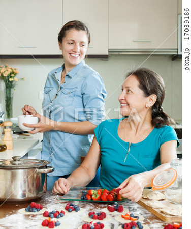 Two smiling women making vareniki with berries Two smiling women making vareniki with berries 17039186