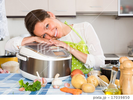Housewife cooking with multicooker. Housewife cooking with multicooker. 17039850