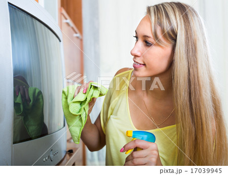 Smiling woman wiping the dust on TV Smiling woman wiping the dust on TV 17039945