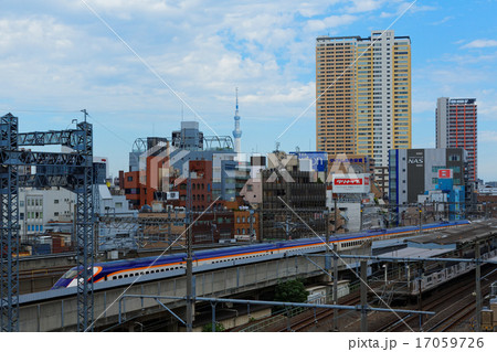 西日暮里駅を通過中の山形新幹線と東京スカイツリーの写真素材