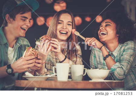 Cheerful multiracial friends eating in a cafe Cheerful multiracial friends eating in a cafe 17081253