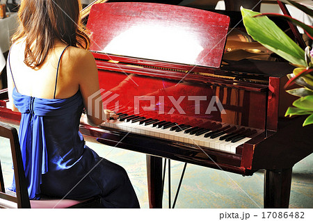 グランドピアノを弾く女性の後ろ姿の写真素材