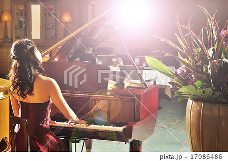 グランドピアノを弾く女性の後ろ姿の写真素材
