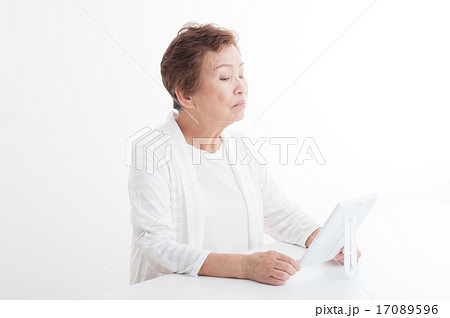 鏡で自分の顔を見ているシニアの女性 17089596